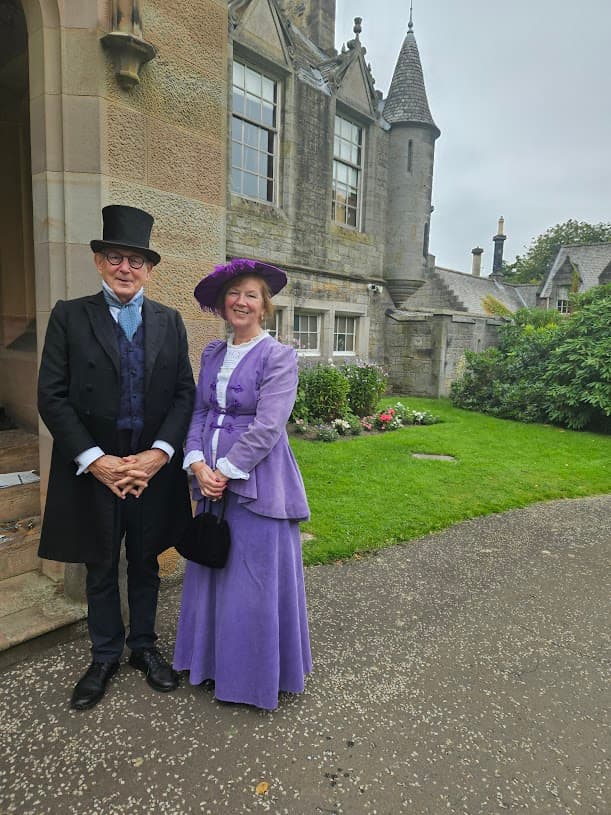A man and women dressed in Edwardian costume stand at the front entrance to a Lauriston Castle