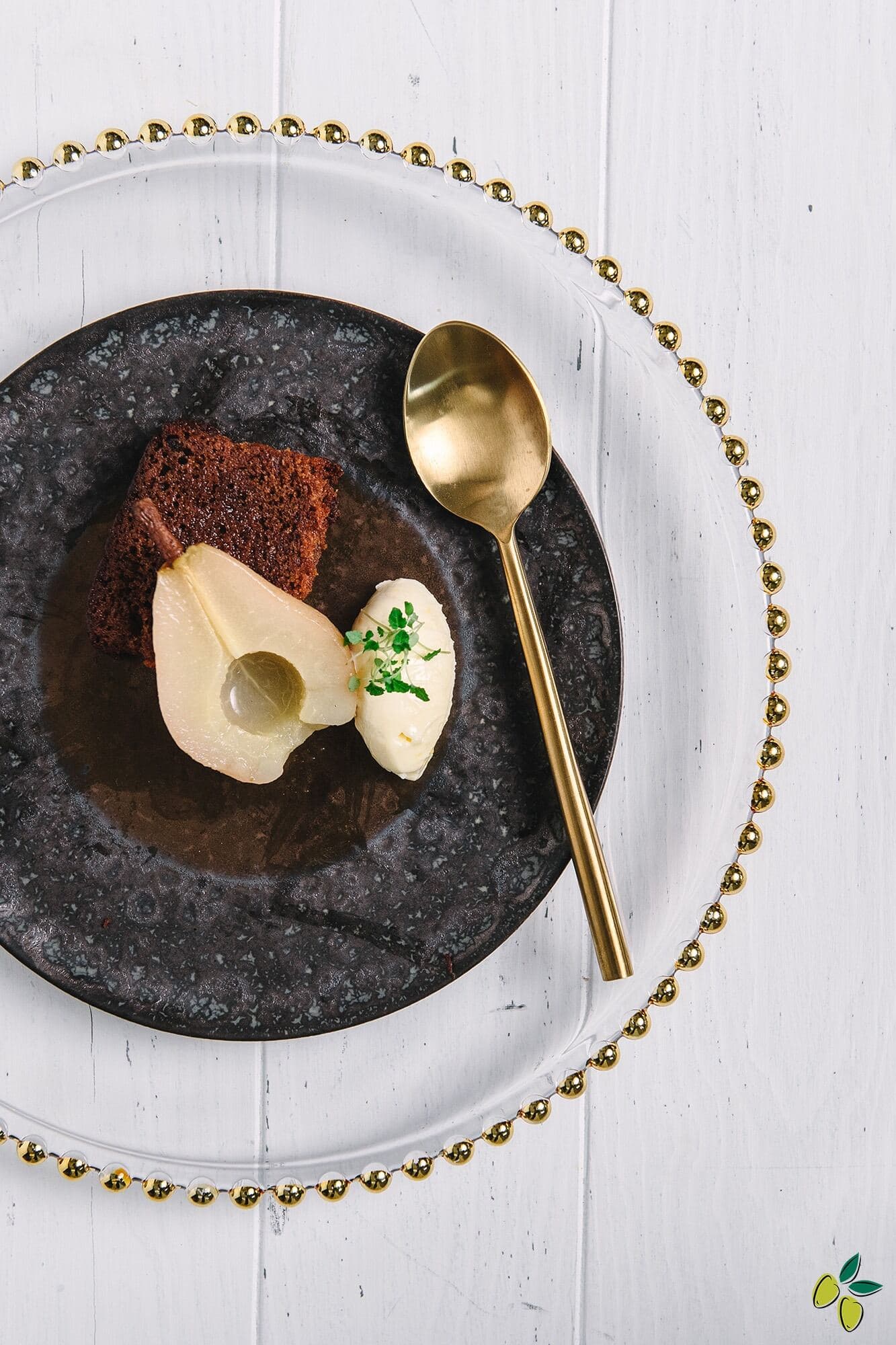 A plate featuring a dessert with a pear and a spoon resting beside it.
