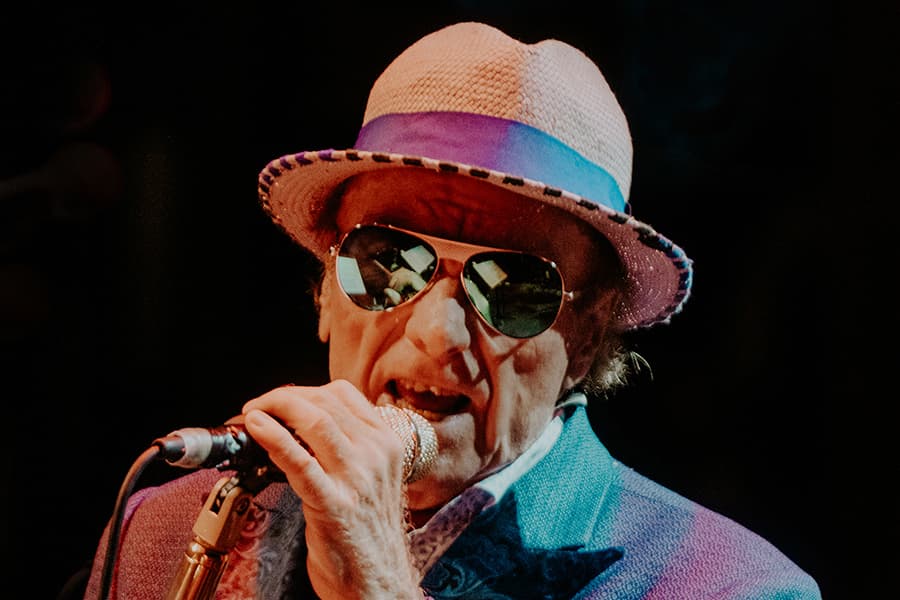 Van Morrison singing in to microphone. Wearing Straw hat and sunglasses