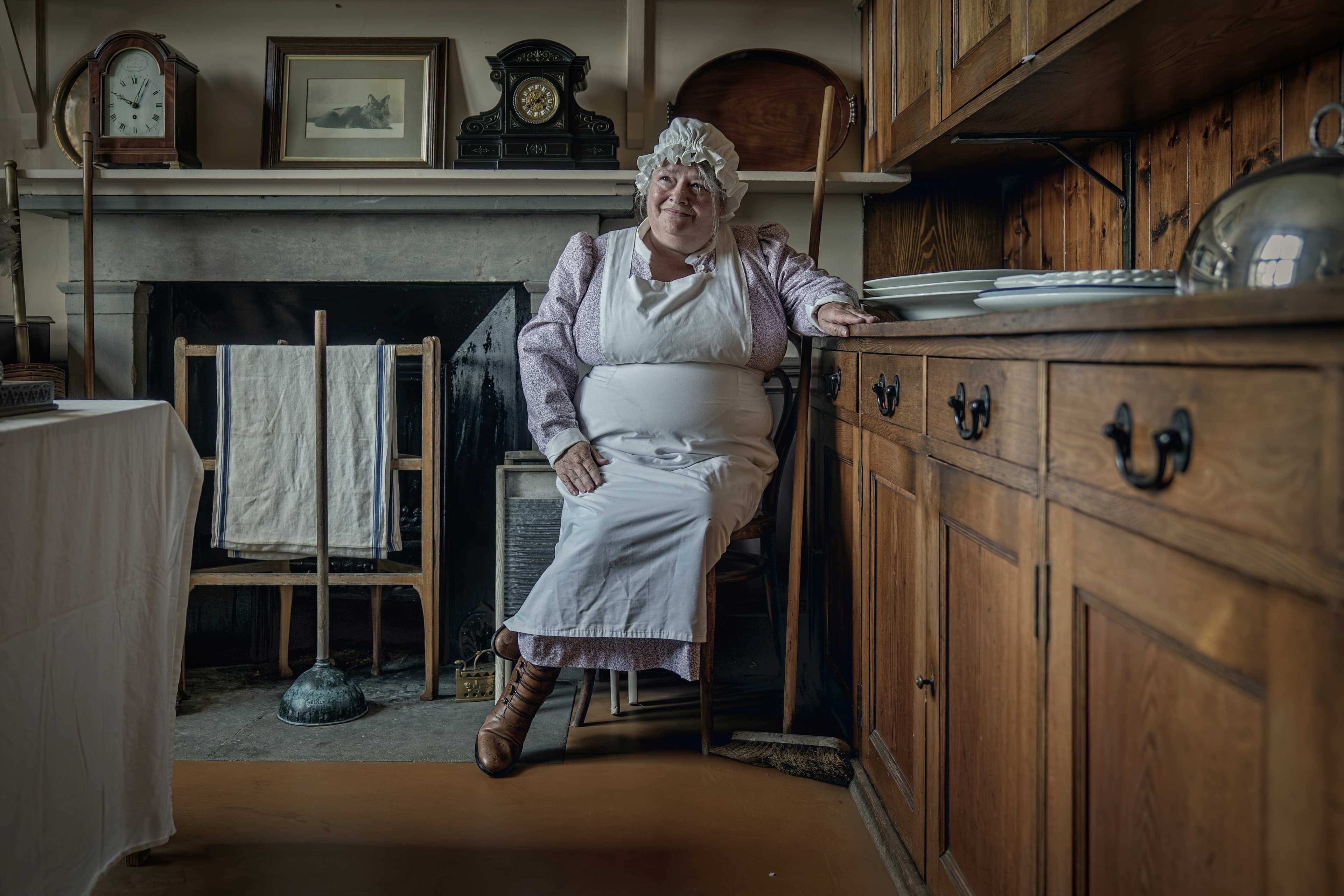 Woman seated in Lauriston Castle kitchen wearing period servant costume