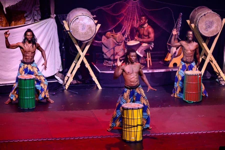 African circus performers hitting drums on a stage