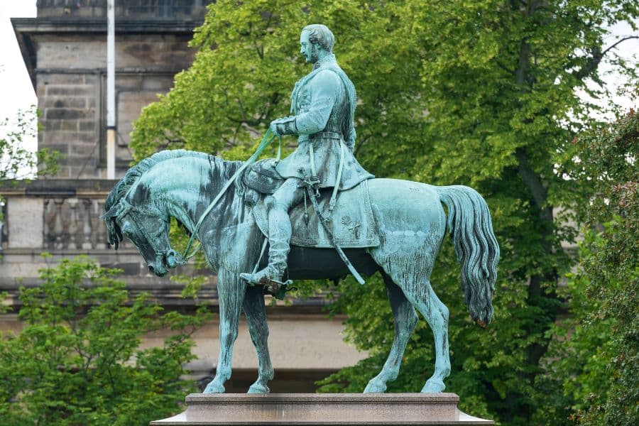 Green statue of a man on top of a horse