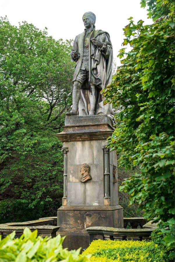 Tall statue of Allan Ramsay surrounded by greenery