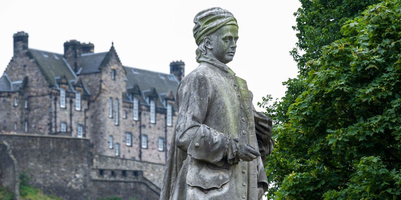 Statue of a young man wearing a headscarf with Edinburgh castle in the background