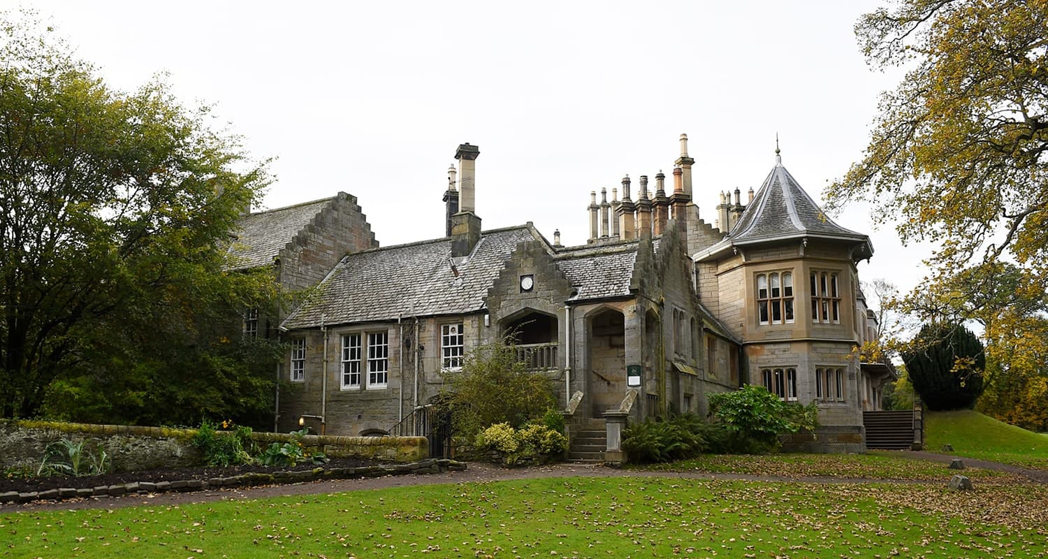 Lauriston Castle. A large stone Edwardian villa, surrounded by a well-maintained garden and trees.