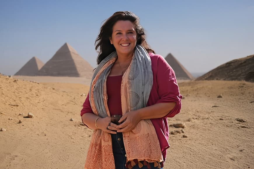 Bettany Hughes in front of the pyramids, highlighting the iconic landmarks of ancient Egypt in the background.