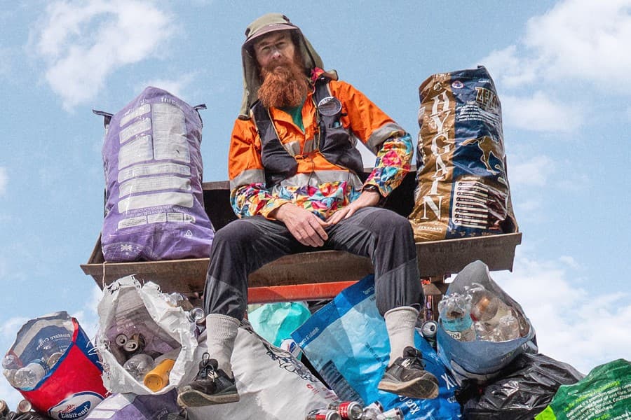 Image shows Beau Miles sitting on a pile of general waste