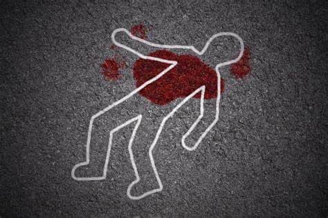 White outline of dead body on pavement with fake blood around top of torso