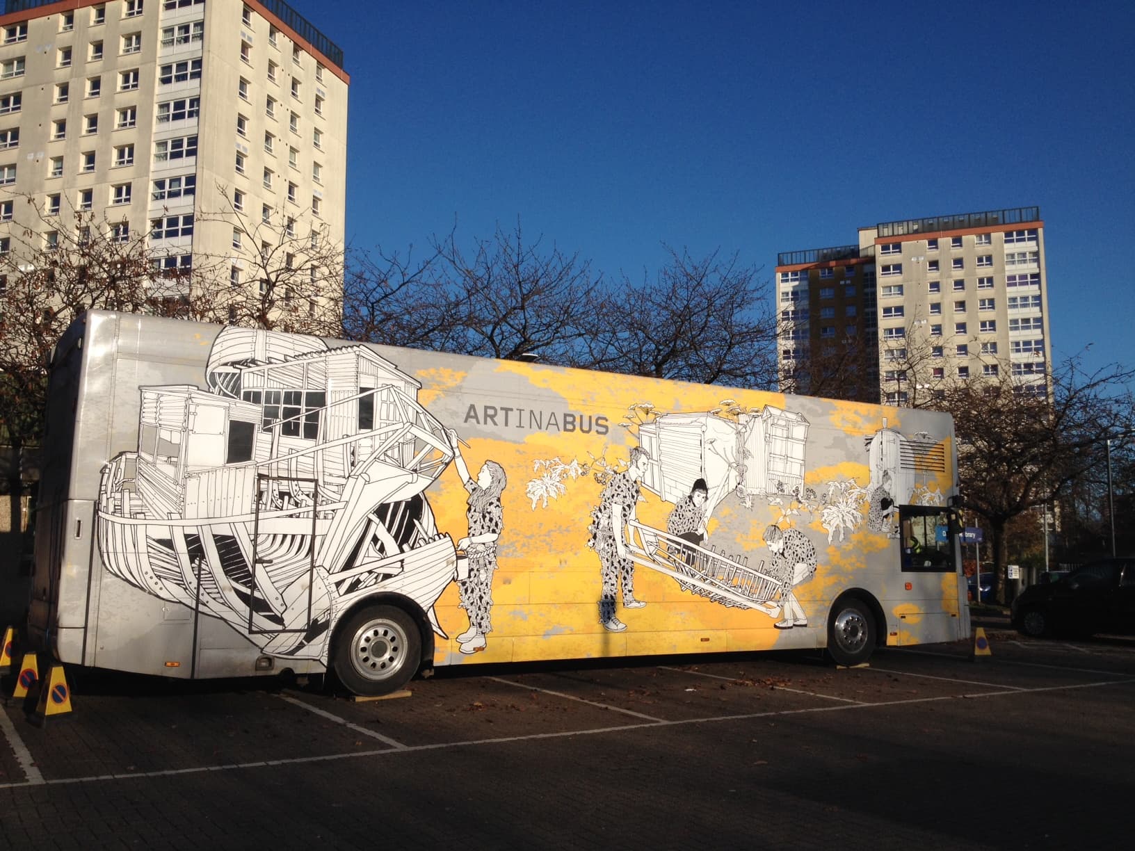 Travelling gallery bus parked up beside flats