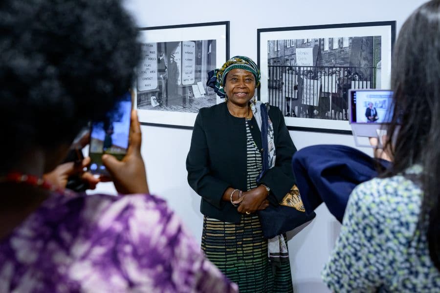 A woman being photographed stood in front of framed pictures taken by Sandra George