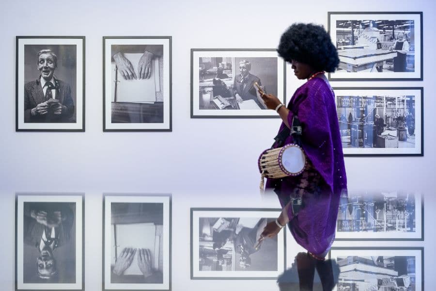 A woman wearing purple stood in front of a wall of framed photographs taken by Sandra George