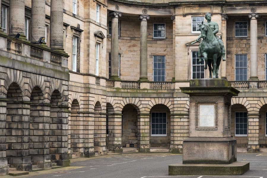 Wide angle shot of a statue of a man riding a horse in a courtyard