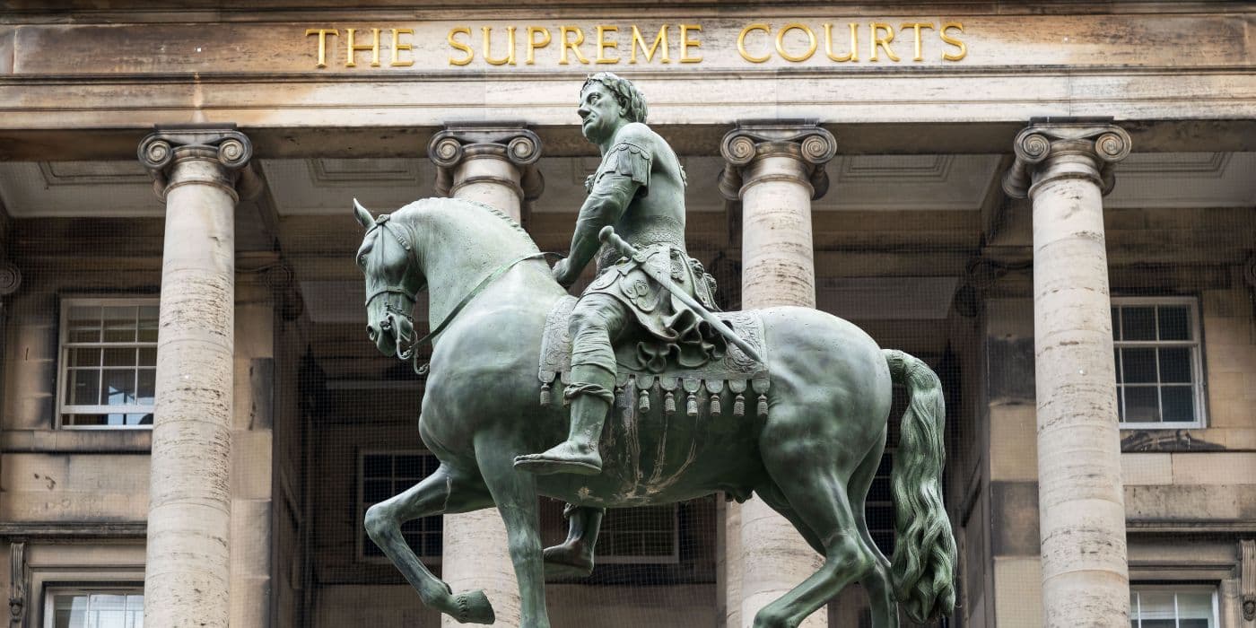 Green statue of a warrior riding a horse in front of the supreme courts