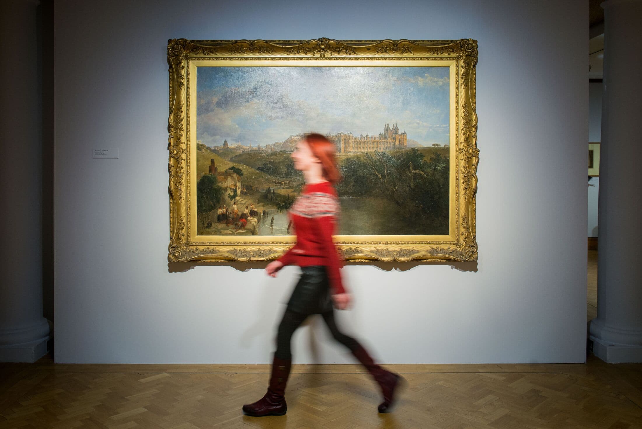 City art centre blurred woman walking past painting