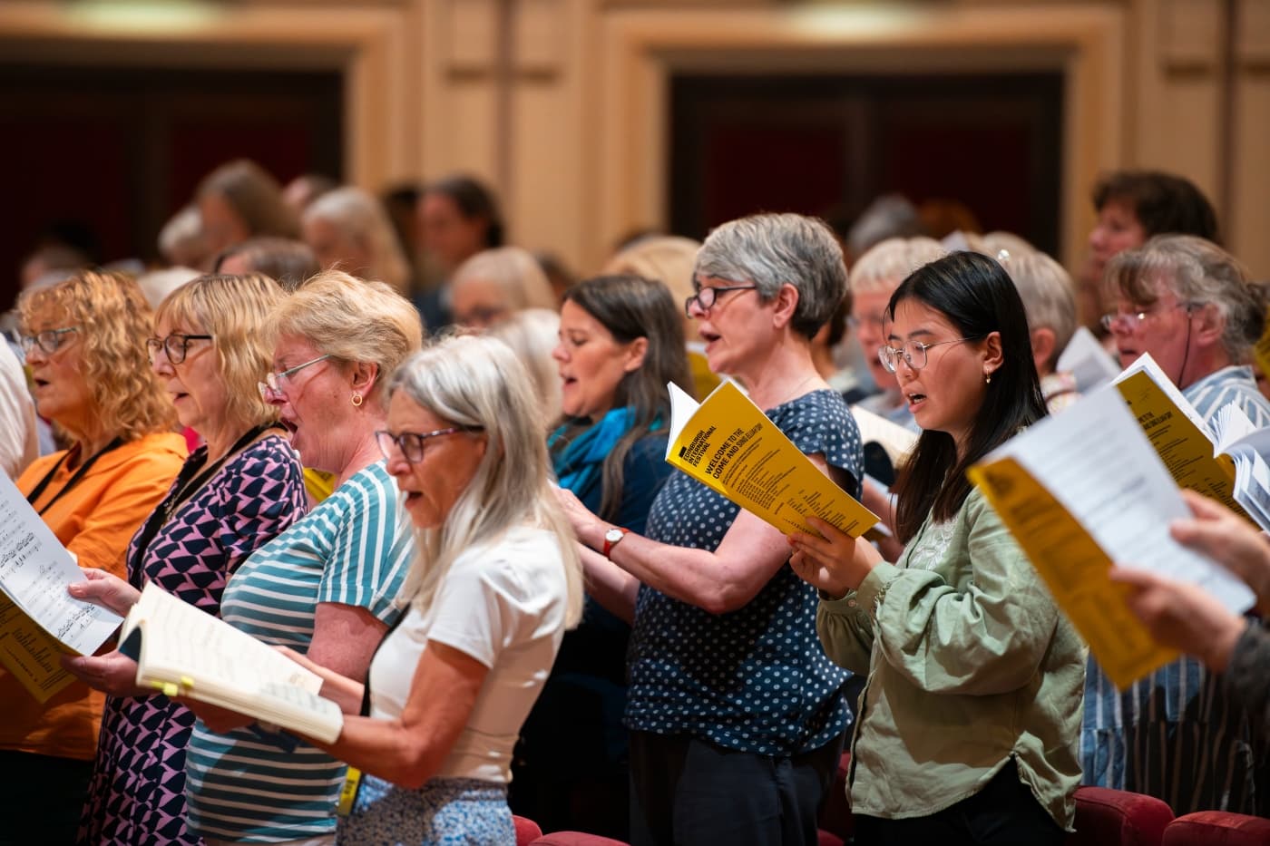 A choir sing hold song booklets and sing proudly as part of the Edinburgh International Festival
