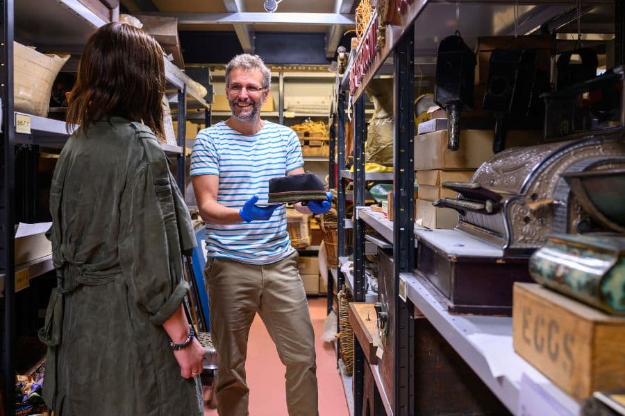 Man showing a hat from museum collections archive to a woman