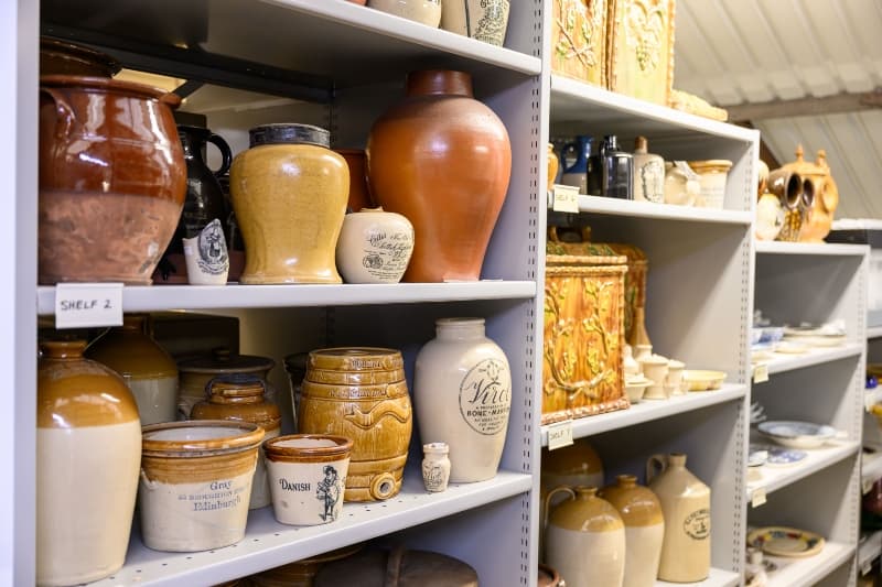 A shelf in Edinburgh's Museum Collection Centre displays an assortment of vases and pots in various shapes and colours