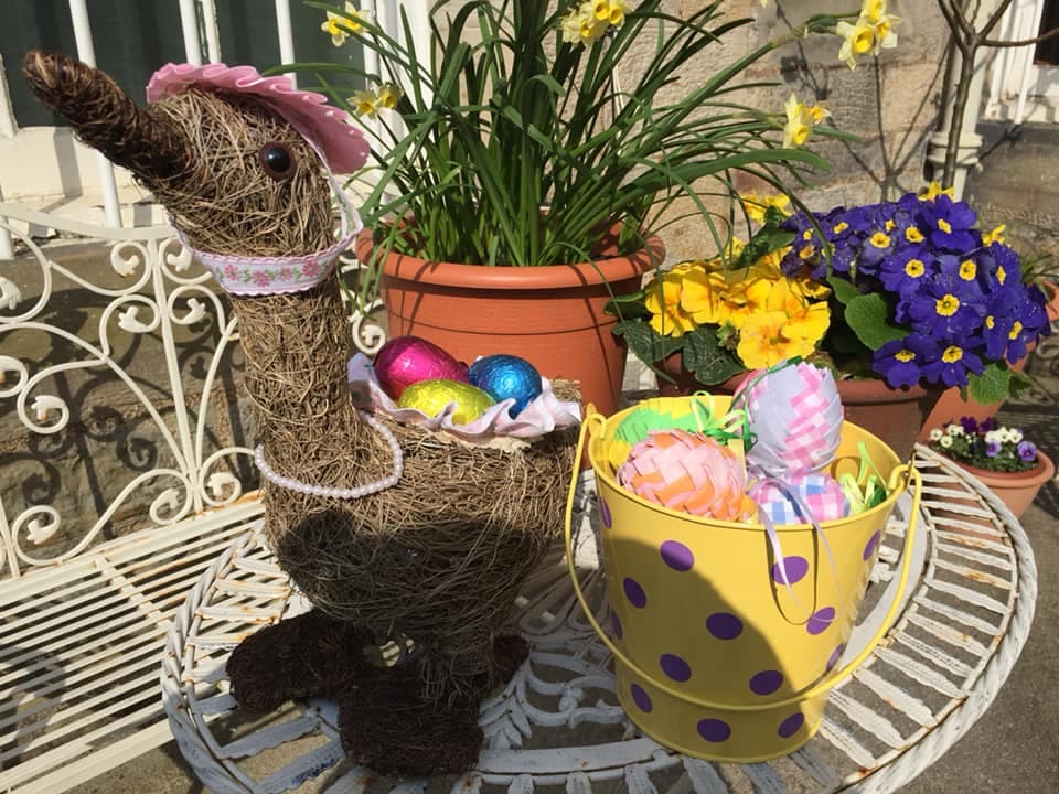 Spring tableau with decorative duck, Easter eggs and daffodils and African violets