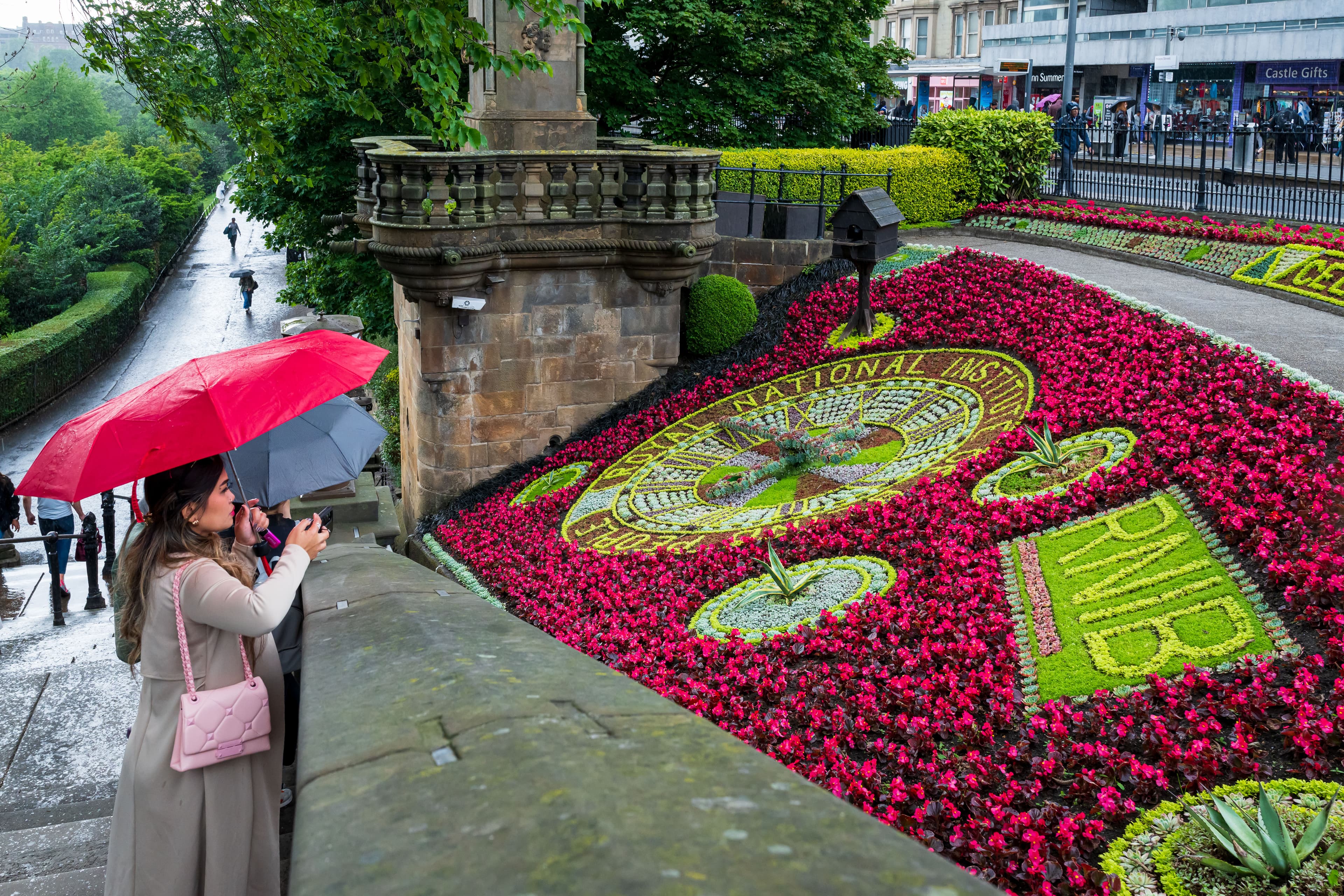 Lady looking over a colourful flower bank in the rain