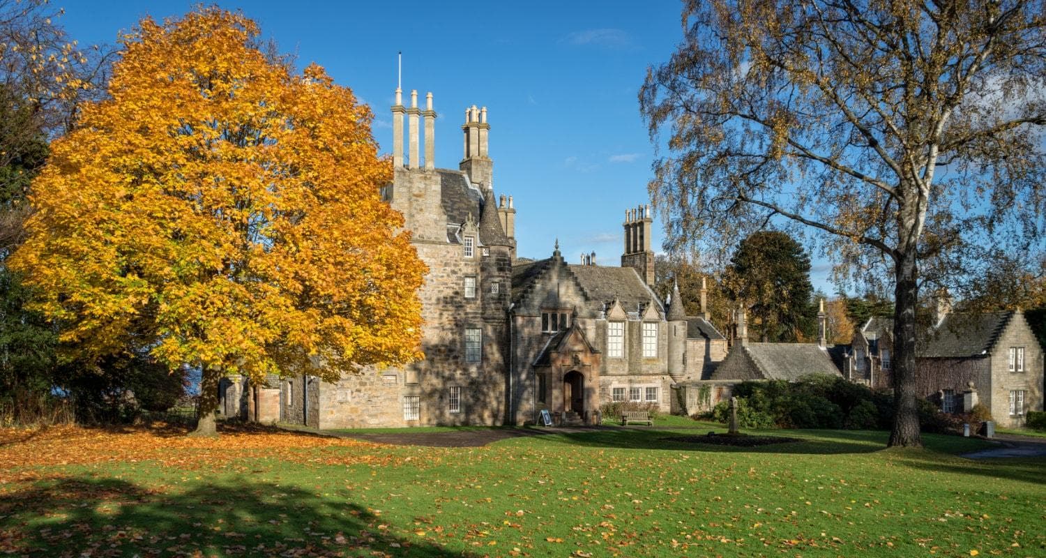 Lauriston Castle in Edinburgh framed by a golden autumnal tree