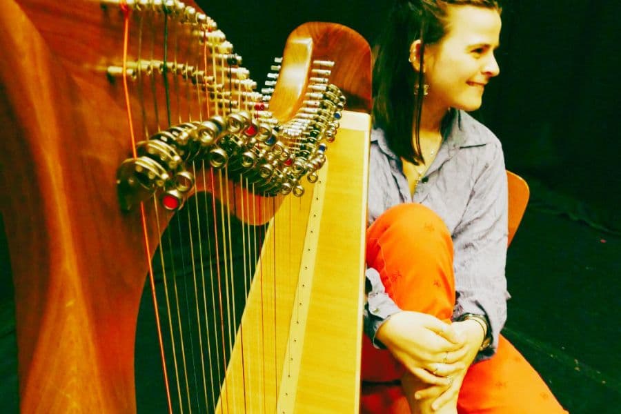 Image shows woman smiling next to clàrsach