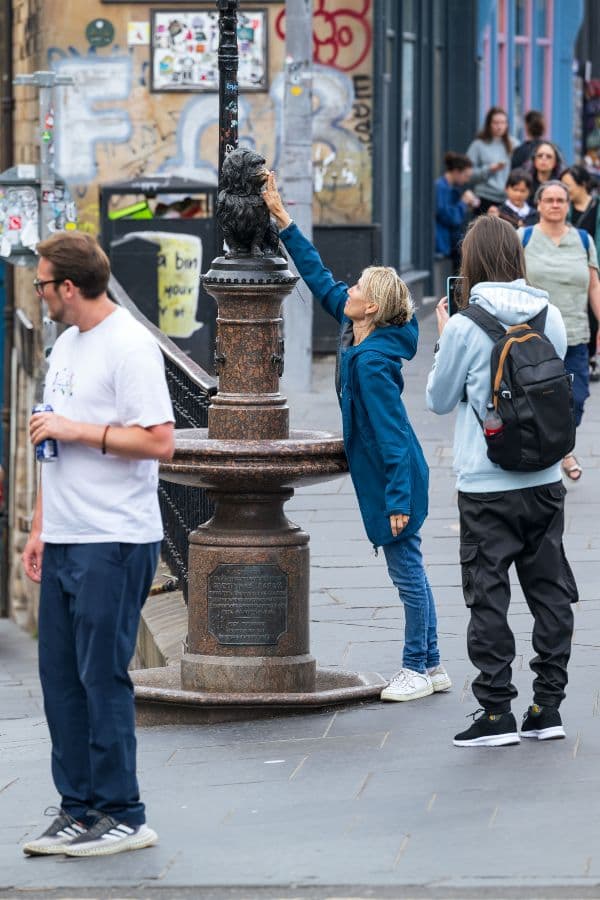 Woman rubbing the nose of Greyfriars bobby statue