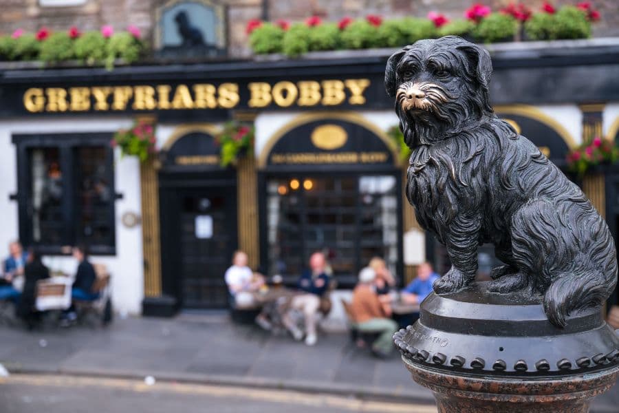Landscape image of a black Skye terrier statue outside Greyfriars bobby pub