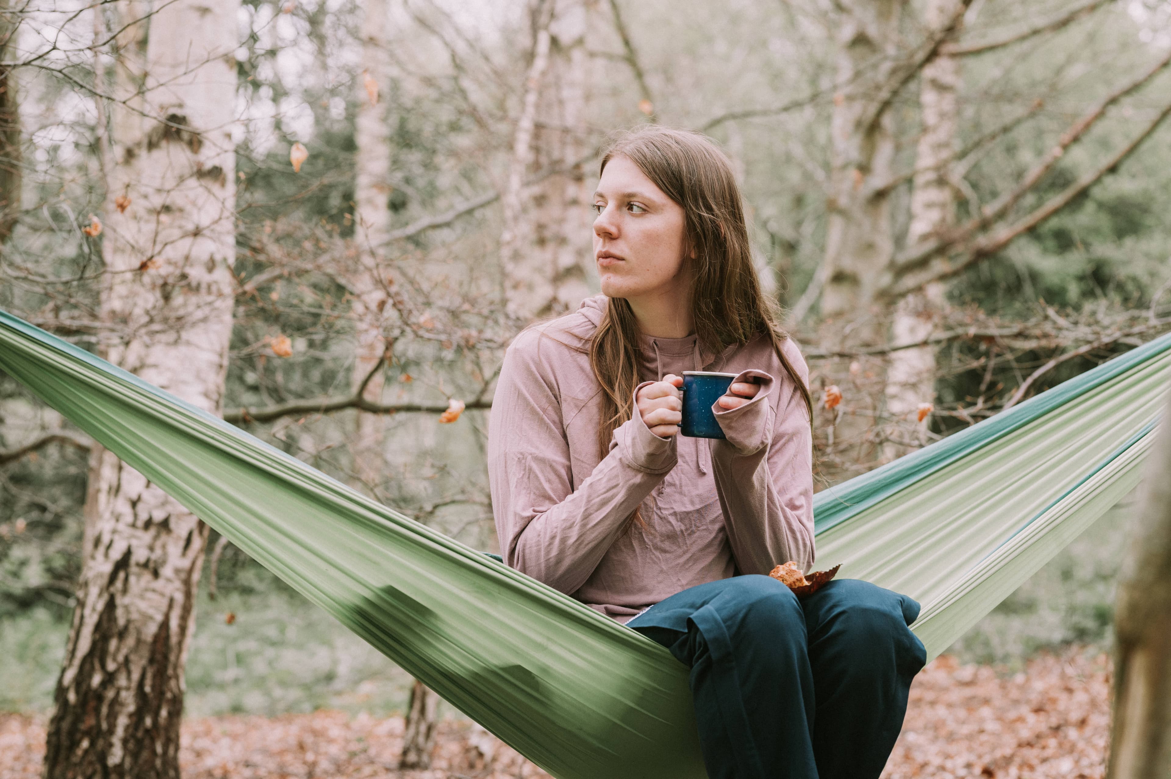 Woman sitting in hammock with mug of tea and muffin
