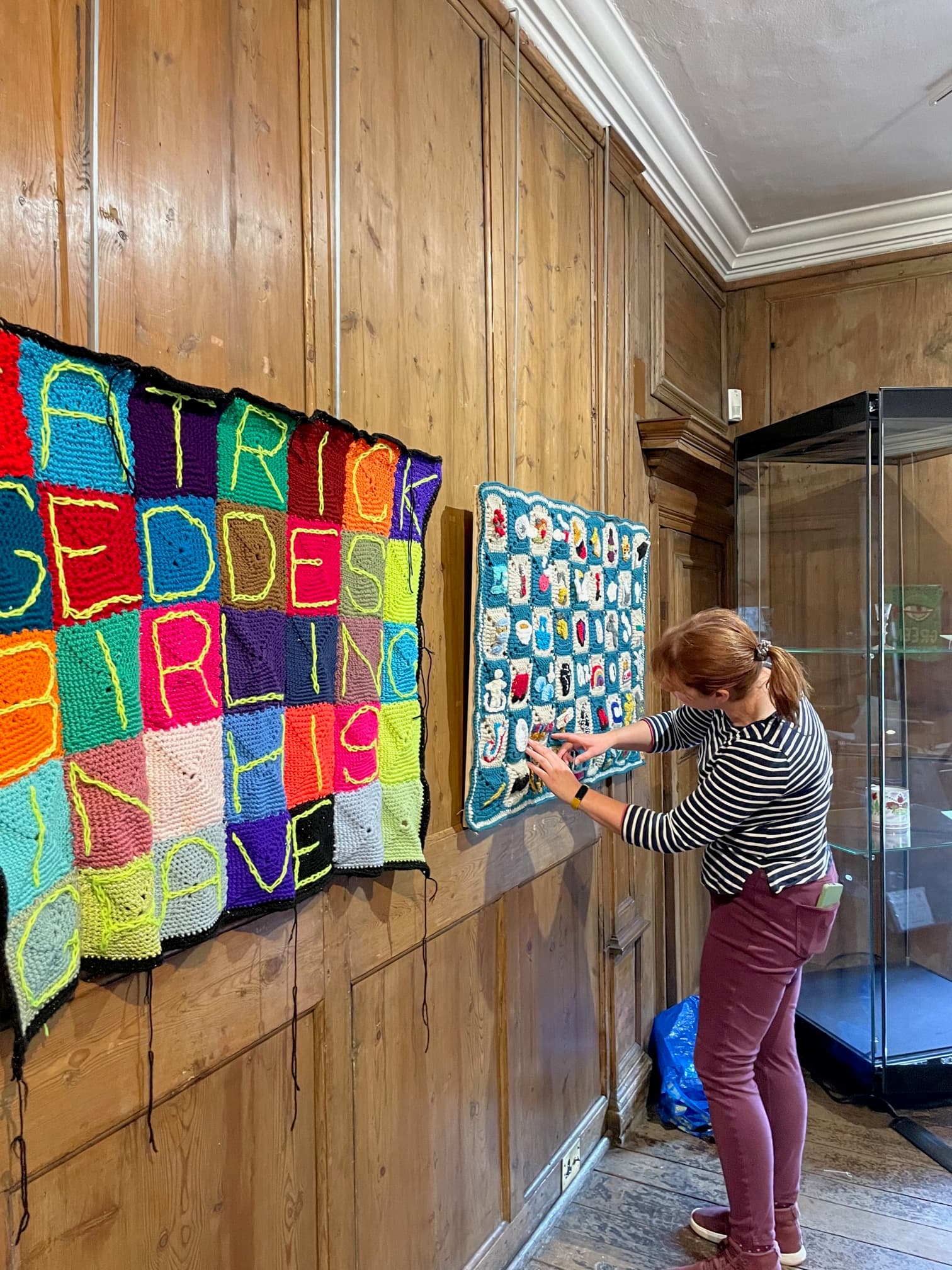 A curator displays a contemporary and colourful tapestry on the wall at the Museum of Edinburgh
