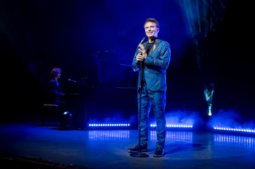 John Barrowman on stage with microphone 