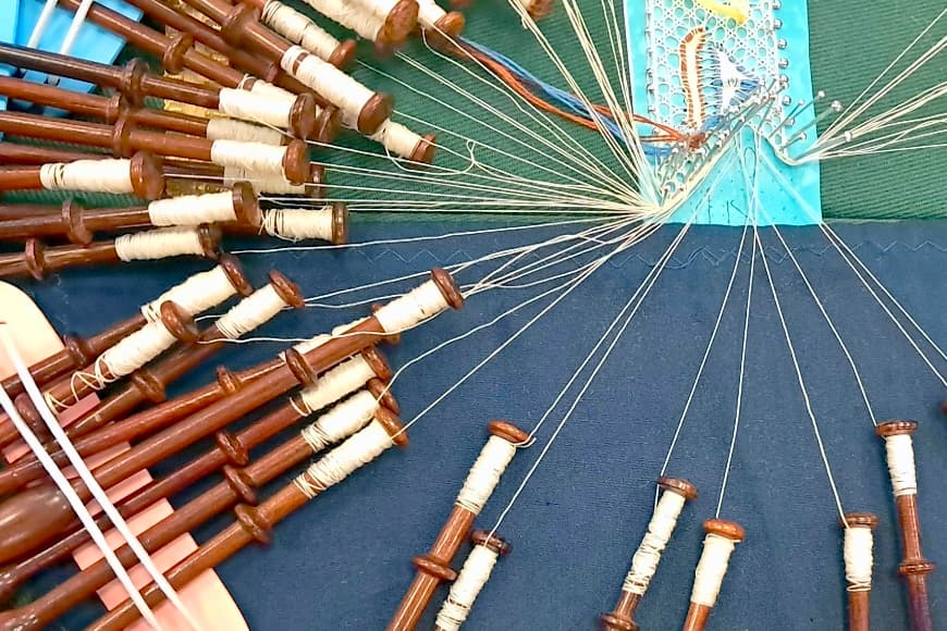 Photo small lace sample being made with bobbins attached