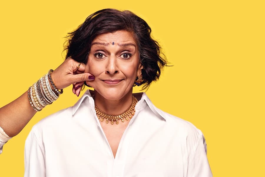 Image shows Meera Syal smiling with hand pinching her left cheek