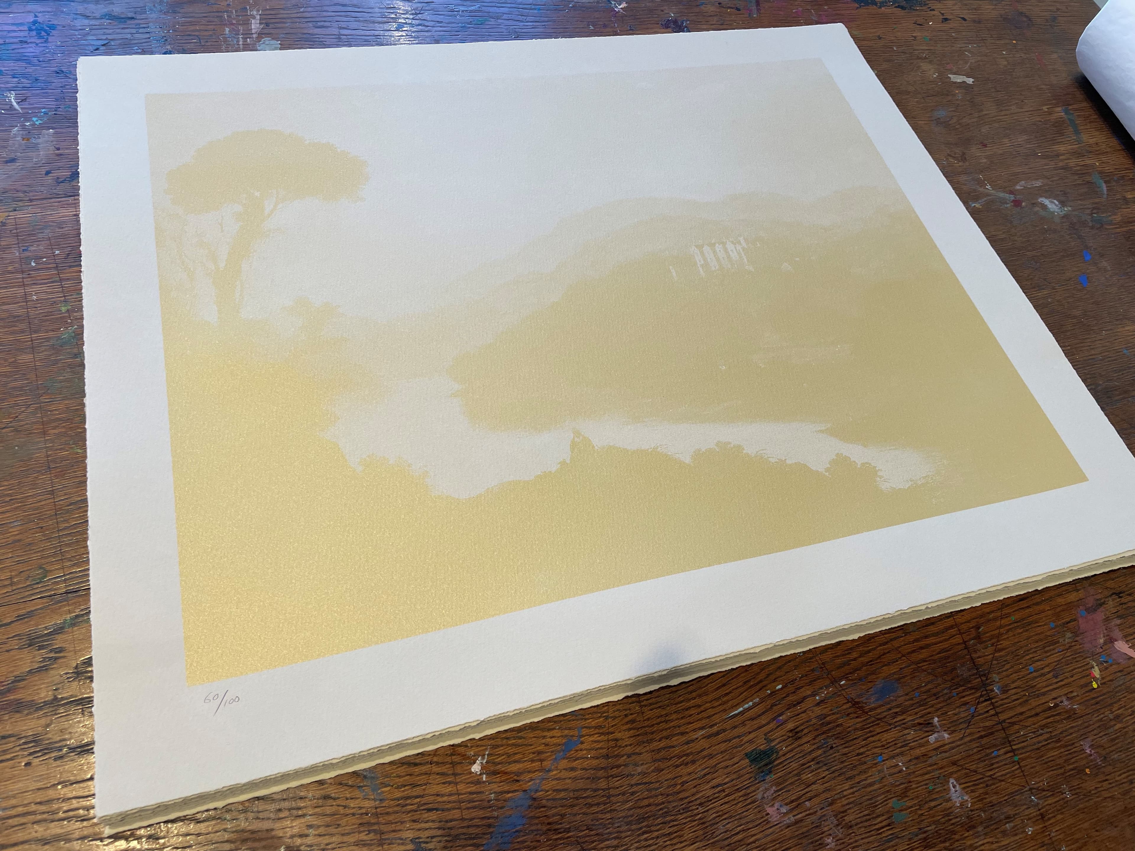A gold screen-print of a view of Walter Scott’s residence in the Scottish Borders. The print, by Scottish artist Michael Fullerton, is on a rustic wooden table. 