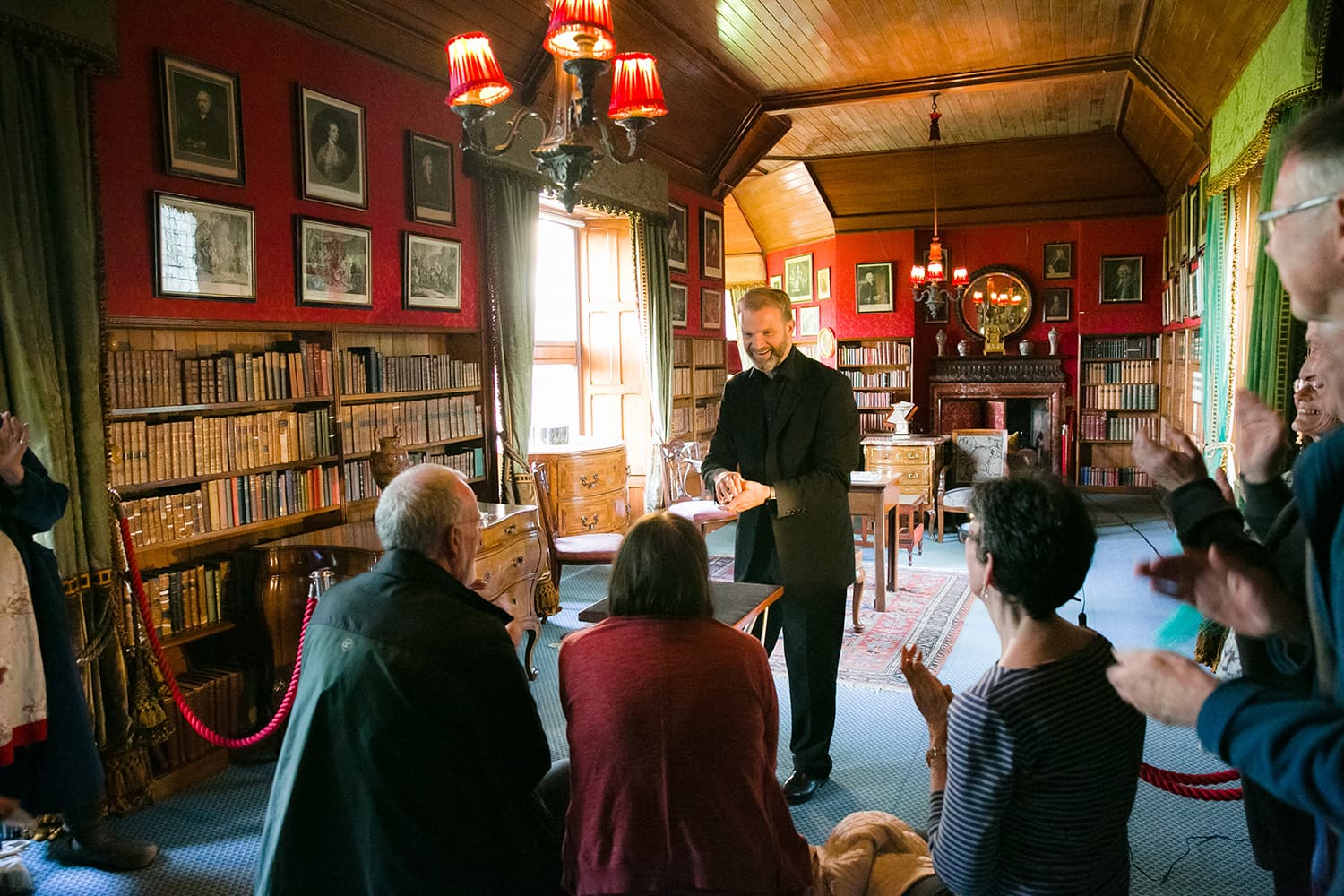 People gathered around a magician performing a card trick