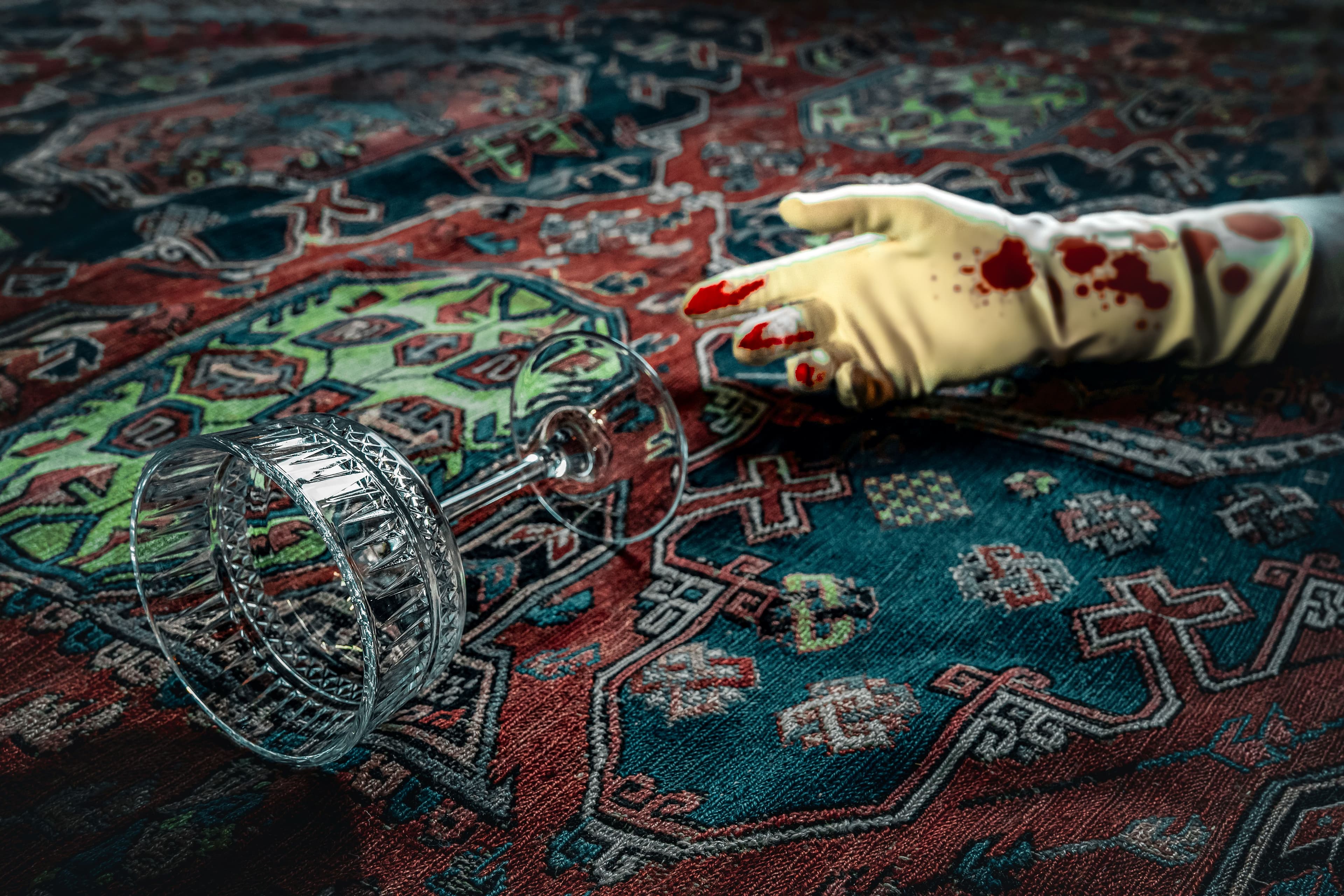 Highly pattered carpet, with a bloodied outstreched gloved hand and dropped wine glass