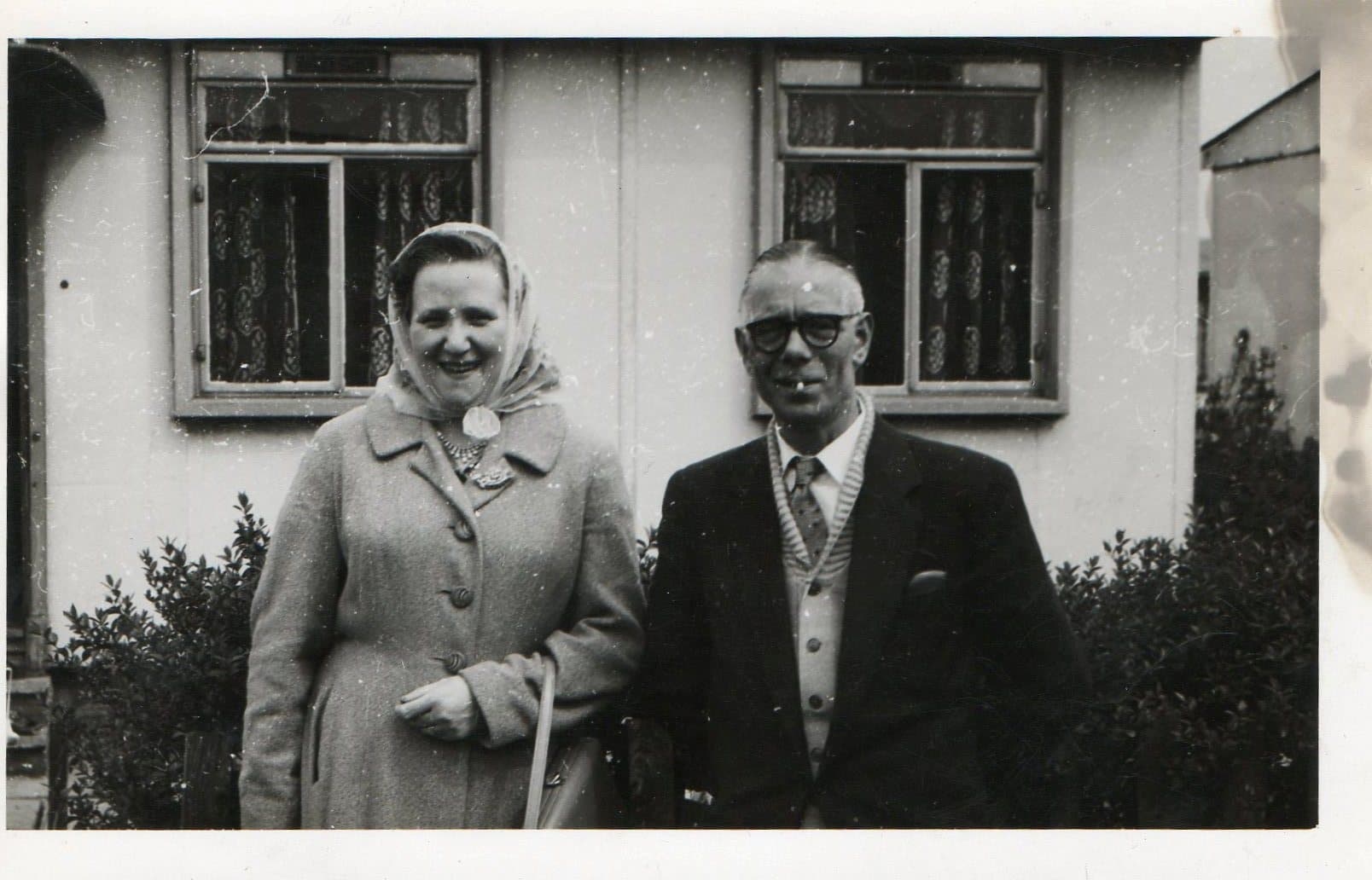 An old black and white photo of an elderly man and woman, both smiling and dressed in clothing from the World War two era