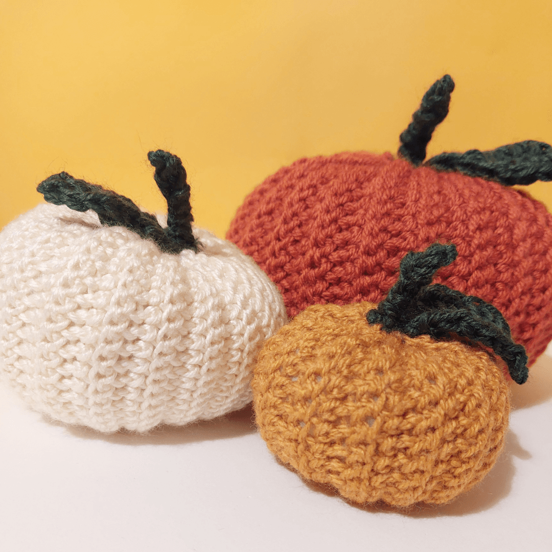 Three crocheted pumpkins in assorted colours