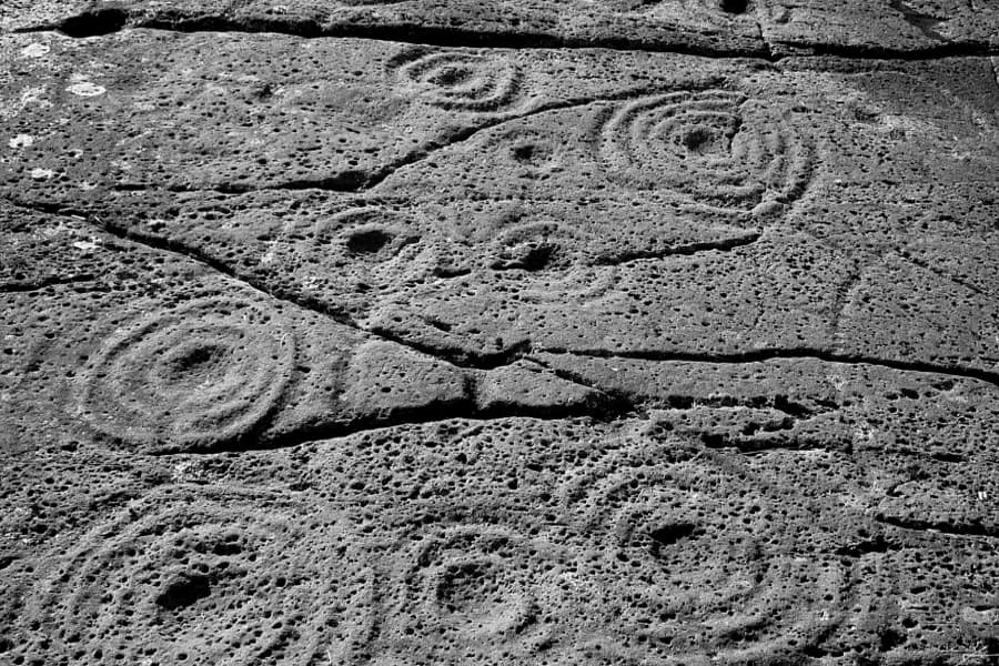 Black and white image of abstract patterns carved in rock