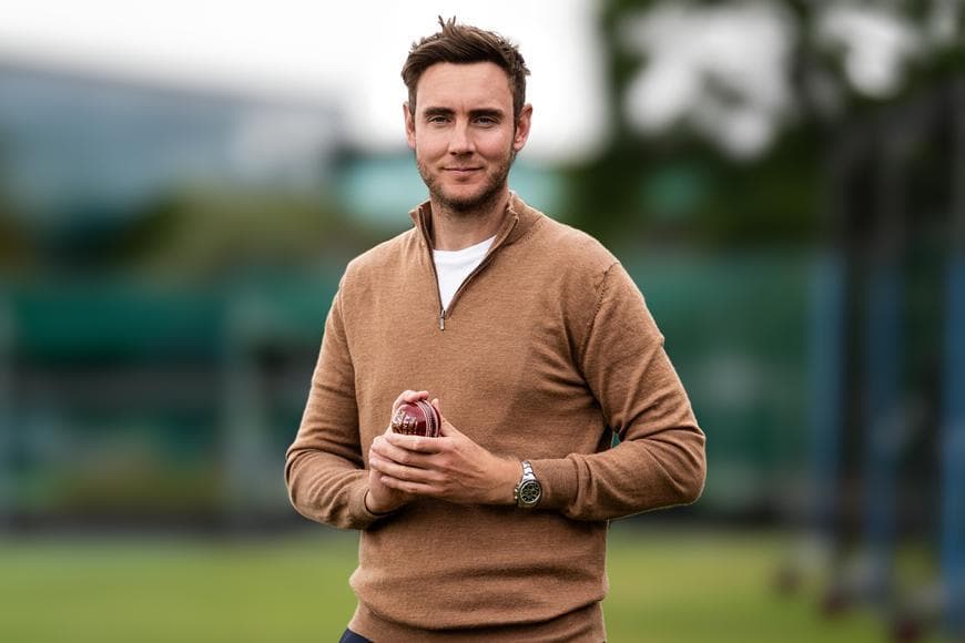 Stuart Broad stood smiling holding a cricket ball 