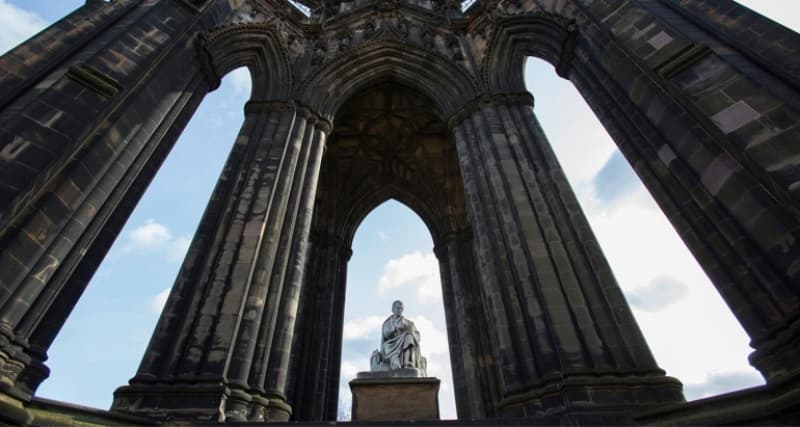 A view looking up at Edinburgh's Scott Monument - a marble statue of Scottish writer Sir Walter Scott is surround by large stone pillars