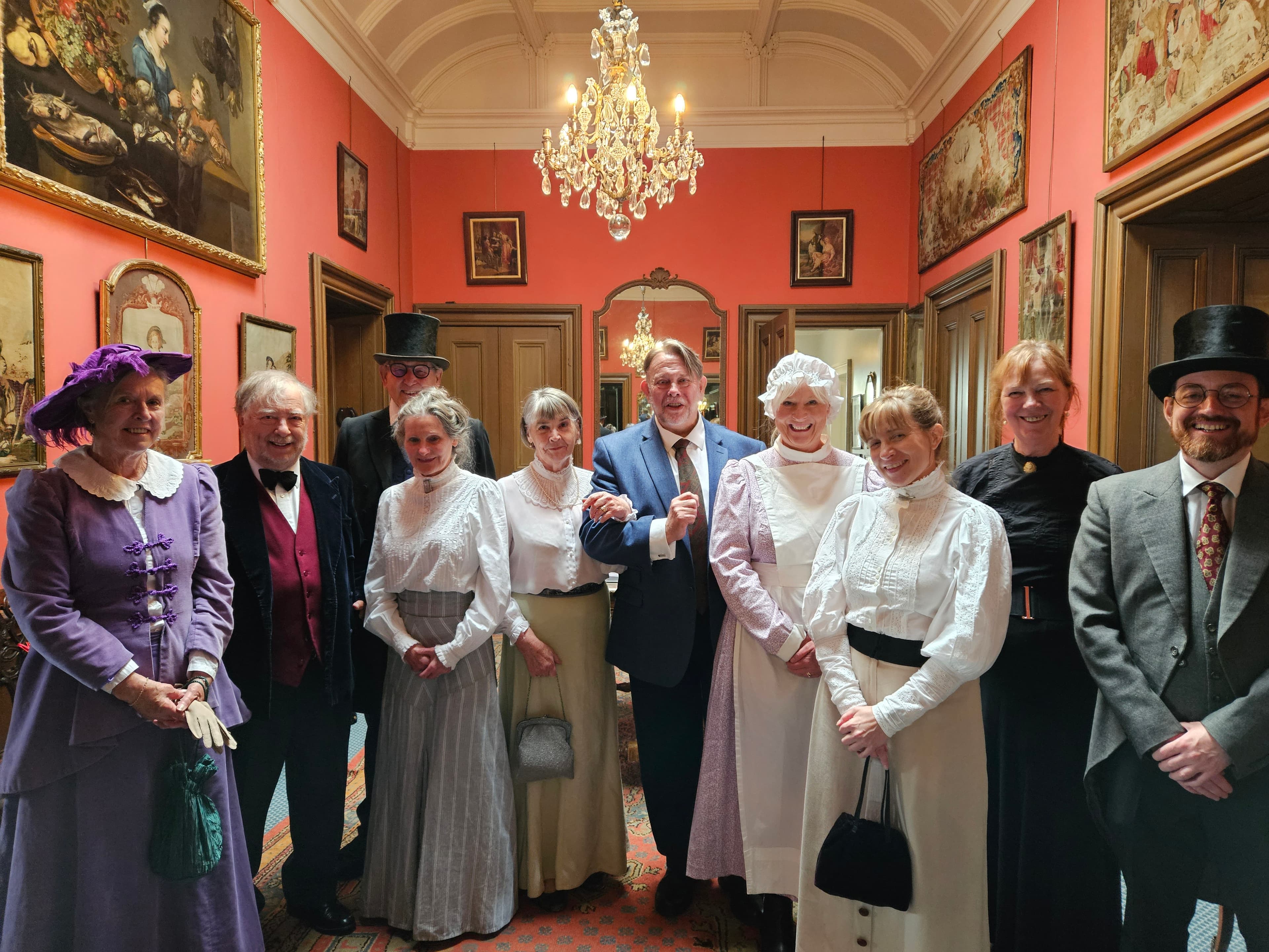 A group of individuals dressed in historical attire poses together for a photograph, showcasing their period costumes