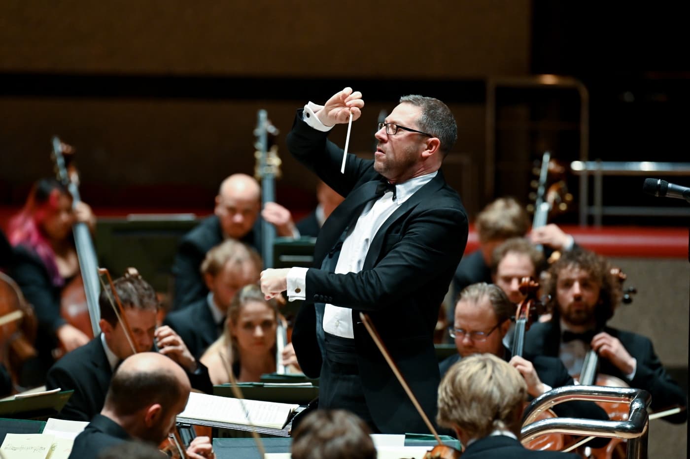 Conductor John Wilson leads an orchestra on stage.