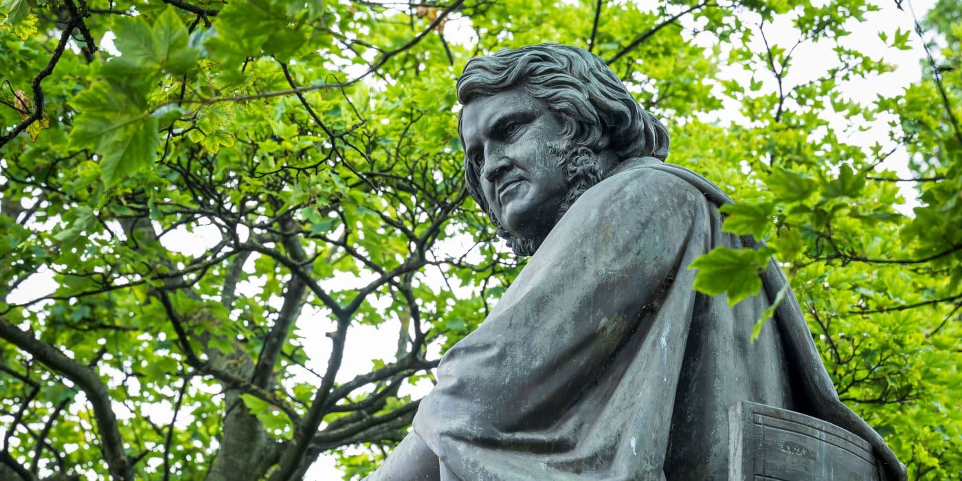 Closeup of statue's face with tree leaves in the background
