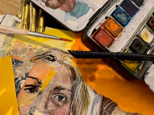 A portrait of a woman's face on a canvas surrounded by paintbrushes and paints