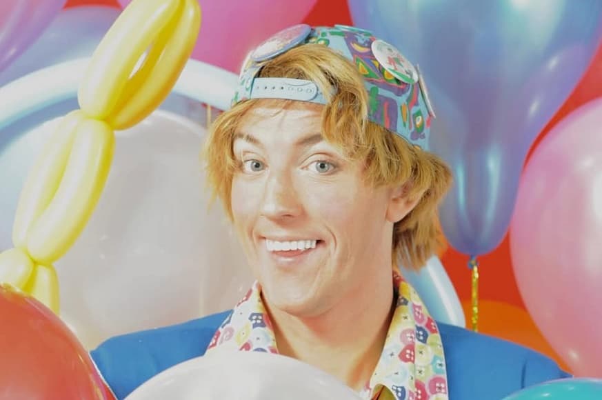 Mr Buttonz smiling surrounded by Balloons