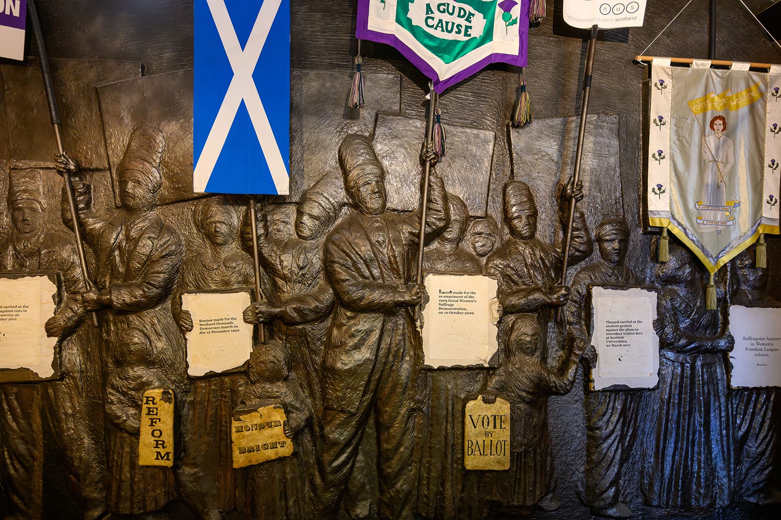 A wall showing a molding of individual people on a wall displaying including numerous flags, showcasing cultural diversity.