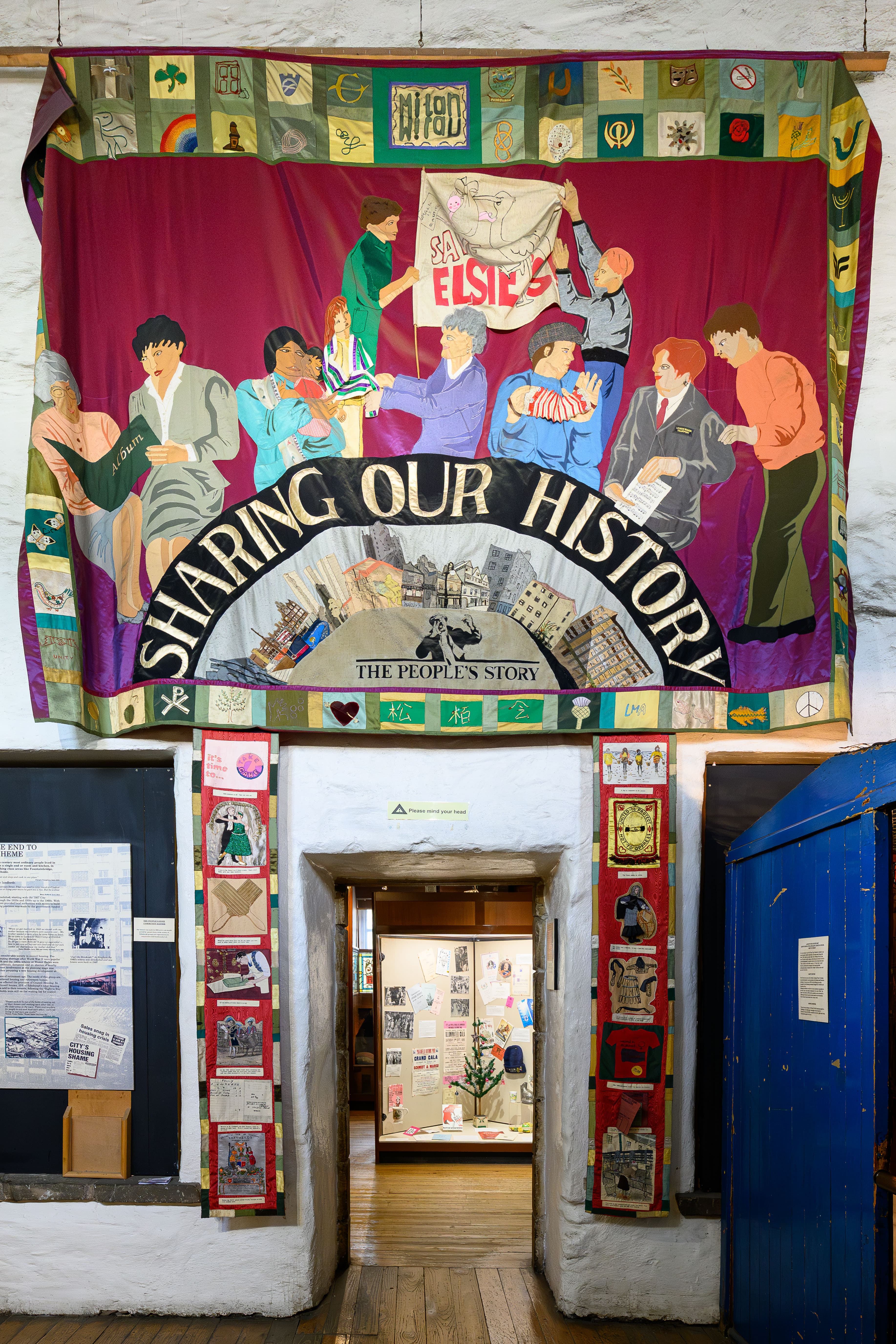 A large banner hanging inside a building, showcasing vibrant designs and information about a special event or initiative.