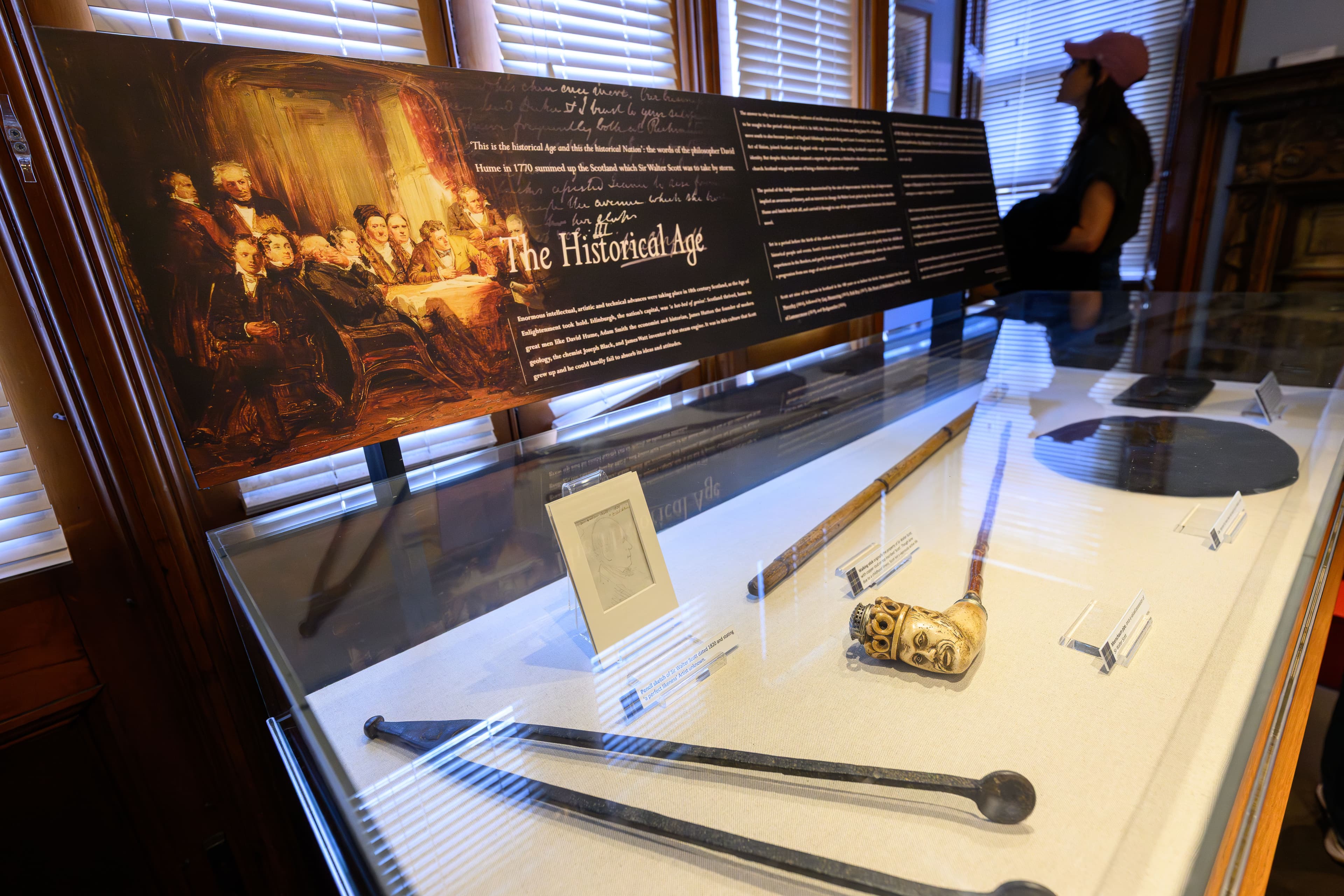 A glass display case filled with an assortment of artifacts including a pipe, clearly visible for examination from the museum visitor.