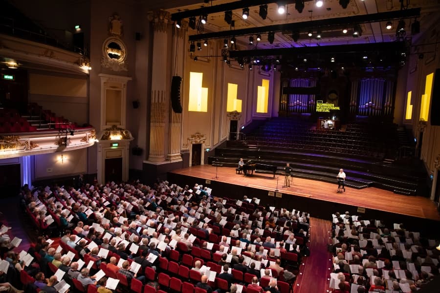 Interior of usher hall showing people reading sheets of music