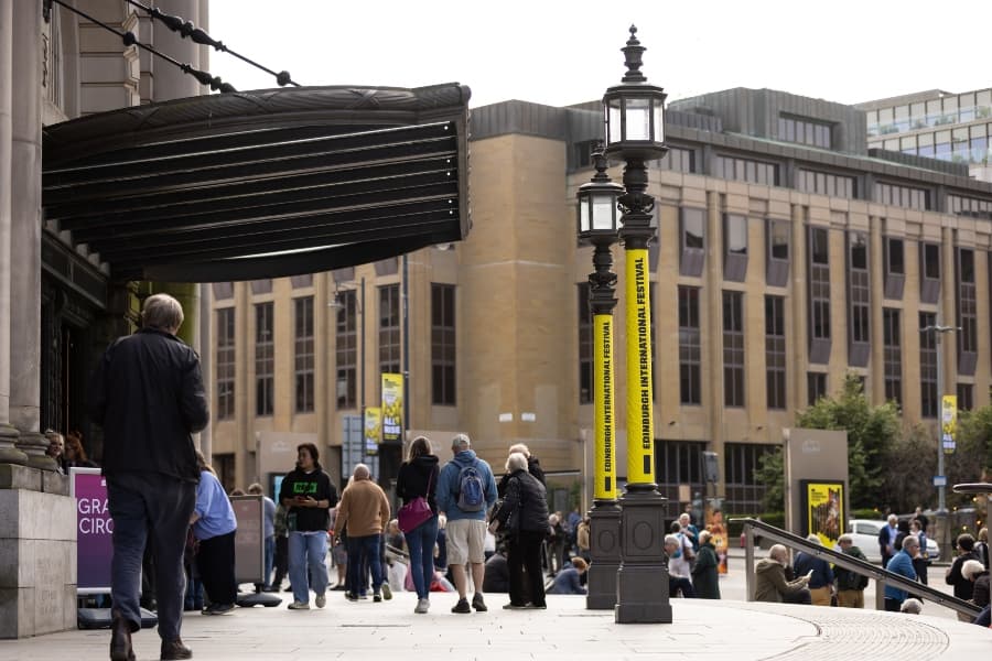 Outside usher hall on a summer's day with yellow EIF branding wrapped around a lamppost